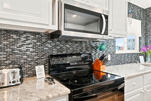 A kitchen with a black stove, a microwave above it, and a toaster on the counter.