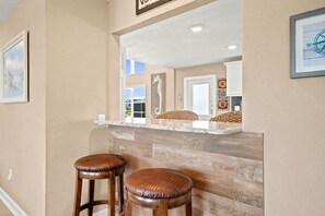 A kitchen with a wooden countertop, two bar stools, and a mirror reflecting the interior.