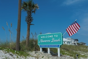 Un cartel da la bienvenida a visitantes a Navarre Beach, Florida, con una bandera estadounidense cerca.