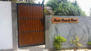 A wooden gate with a sign reading "Dasa Beach View" and a concrete wall with small plants. - Dasa Beach View (Koggala)