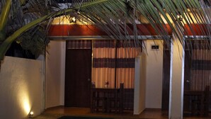 A covered outdoor area with a wooden table and chairs, a door, and a palm tree. - Dasa Beach View (Koggala)
