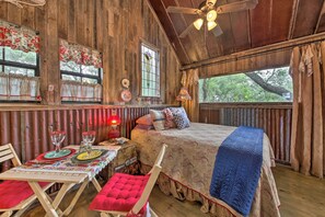 Una habitación rústica de madera con una cama, una mesa para dos personas y una ventana con cortinas.