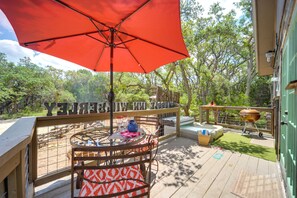 Una terraza con mesa y sillas, una parrilla y un paraguas rojo.