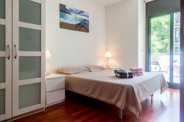Enjoy a restful night's sleep in this cozy bedroom with a single bed, nightstand, and wall-mounted lamp, offering a view of the outdoors through the large window.