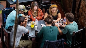 A group of people seated around a table in an outdoor setting, possibly a café or restaurant. - Wanderthirst Hostel (Kathmandu)