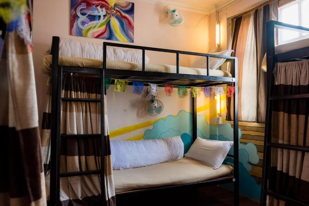 A bunk bed room with a colorful mural, a fan, and curtains.