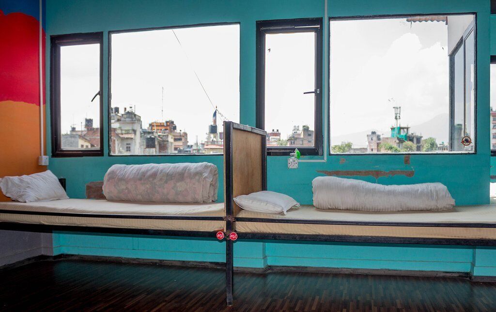 Une chambre avec deux lits superposés, de grandes fenêtres et une vue sur le paysage urbain.