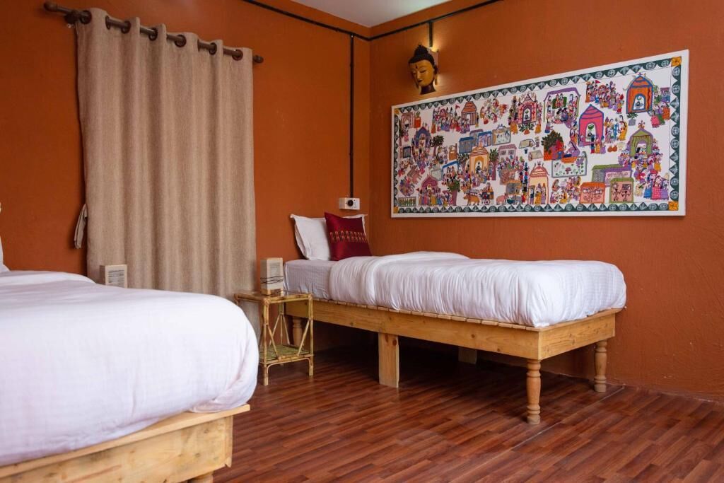 A room with two wooden beds, a large mural on the wall, and a curtain.