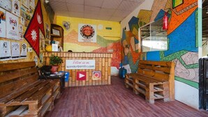 A cozy hostel interior with wooden benches, a sign for Wanderlust Hostel, and colorful wall art. - Wanderthirst Hostel (Kathmandu)
