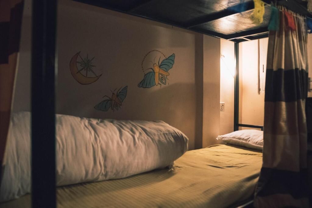 Un letto singolo con testiera, una parete con una falce di luna e due uccelli, e un tendaggio parzialmente visibile.
