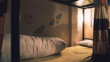 Un letto singolo con testiera, una parete con una falce di luna e due uccelli, e un tendaggio parzialmente visibile.