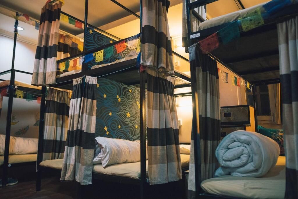 A dormitory room with bunk beds, each with a unique patterned headboard.