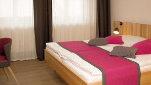 Ein Hotelzimmer mit einem Bett, einem Sessel und einem Nachttisch.