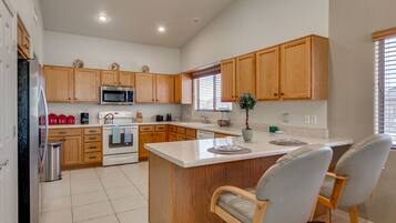 A modern kitchen with wooden cabinets, a central island, and two bar stools.
