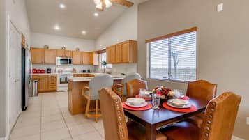 A spacious kitchen with wooden cabinets, a dining table set for four, and a ceiling fan.