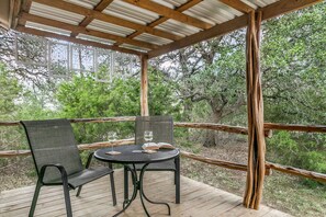 An outdoor patio with a table and chairs, surrounded by wooden railings and trees.