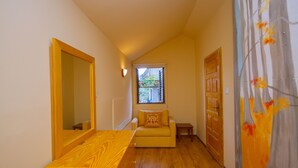 Un couloir étroit avec un banc en bois, un canapé avec un coussin, une fenêtre donnant sur un paysage et une porte.