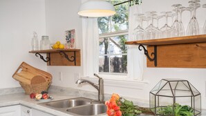 Una cocina con un lavamanos doble, estantes de madera, una lámpara colgante y una ventana con vistas.