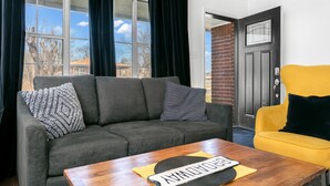 Una sala de estar con un sofá gris, un sillón amarillo y una mesa de centro de madera.