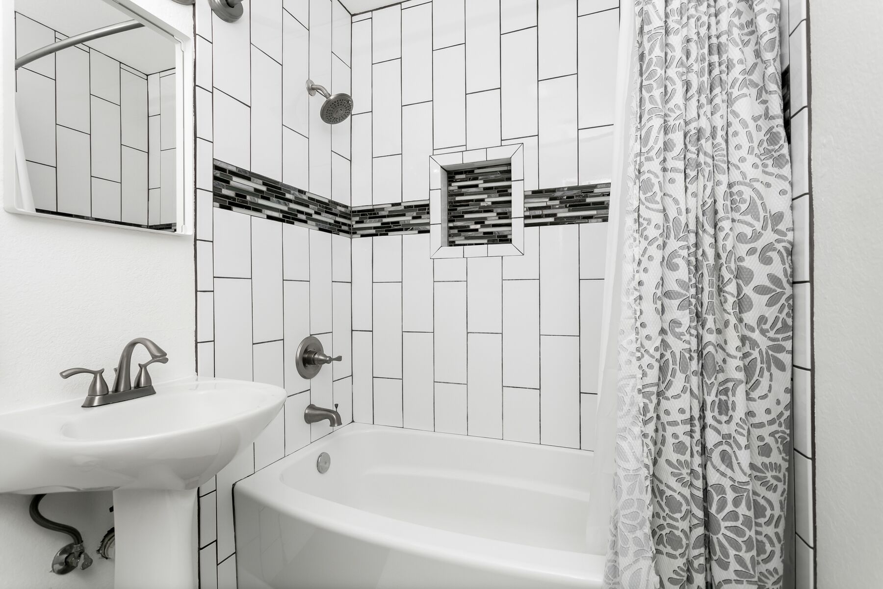 Un baño con lavamanos blanco, bañera y ducha con cabezal de lluvia.