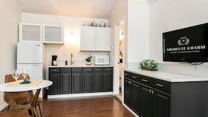 A compact kitchen with dark cabinets, a white countertop, and a dining area with a round table and chairs. - Downtown Retreat Simply Unforgettable | Walk to Main | Shared Pool & Hot Tub (Fredericksburg)