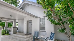 A white house with a covered porch, two rocking chairs, and a small table with two glasses.