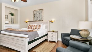 A bedroom with a wooden bed, bedside tables, a chair, a round table, and a ceiling fan.