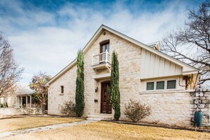 Une maison en pierre dotée d’un balcon, d’un porche et d’une pelouse bien entretenue.