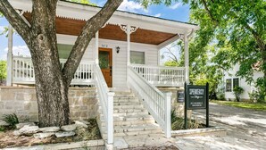 A white building with a porch, stone steps, and a sign indicating Speakeasy Cottages.