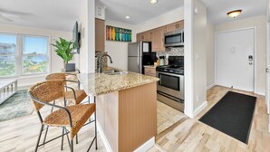 Uma cozinha moderna com ilha central, eletrodomésticos de aço inoxidável e vista para o exterior.