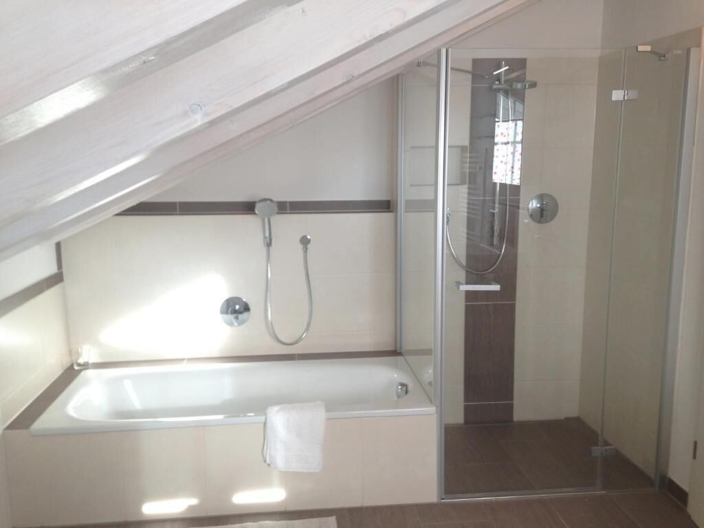 Ein modernes Badezimmer mit Badewanne, Dusche und einer Glaskabine für die Dusche.