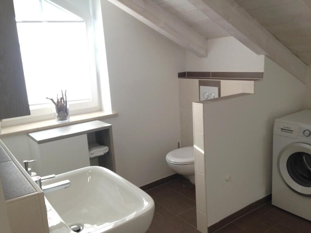 Une salle de bain de taille réduite, équipée d’une baignoire, de toilettes et d’un lave-linge.