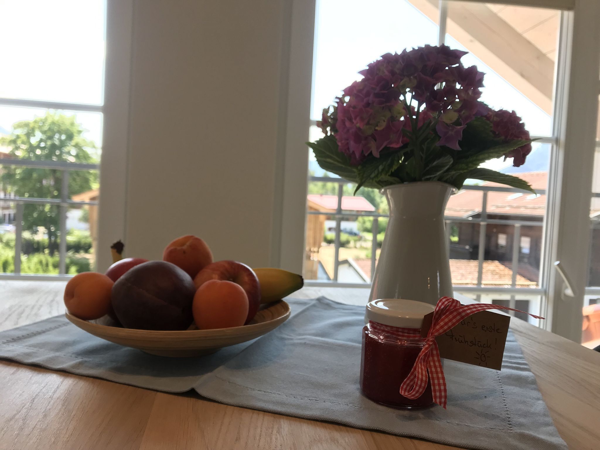 Une table en bois avec un saladier de fruits et un vase de fleurs.
