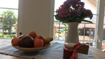 Une table en bois avec un saladier de fruits et un vase de fleurs.