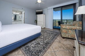 Une chambre d’hôtel avec un lit, une chaise, une télévision, une armoire et un balcon avec vue.