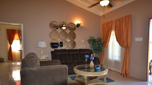 A living room with a sofa, armchair, coffee table, and wall-mounted mirrors. - The Monet Place (Ocho Rios)