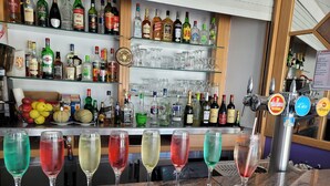 Zona de bar con diferentes botellas de licor y vasos.