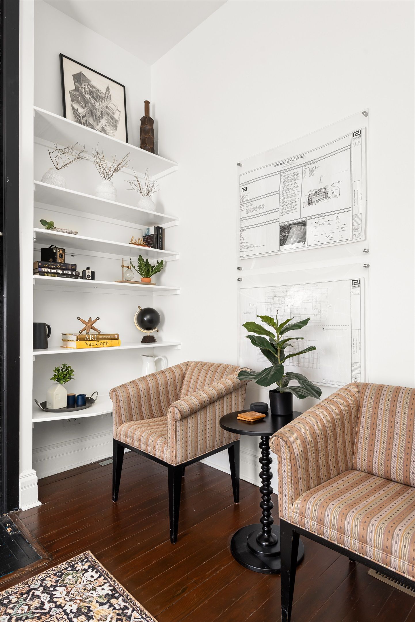 A modern living room with striped armchairs, a coffee table, and a bookshelf with decorative items.