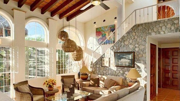 A spacious living area with a stone wall, a sofa set, and a hanging light fixture.