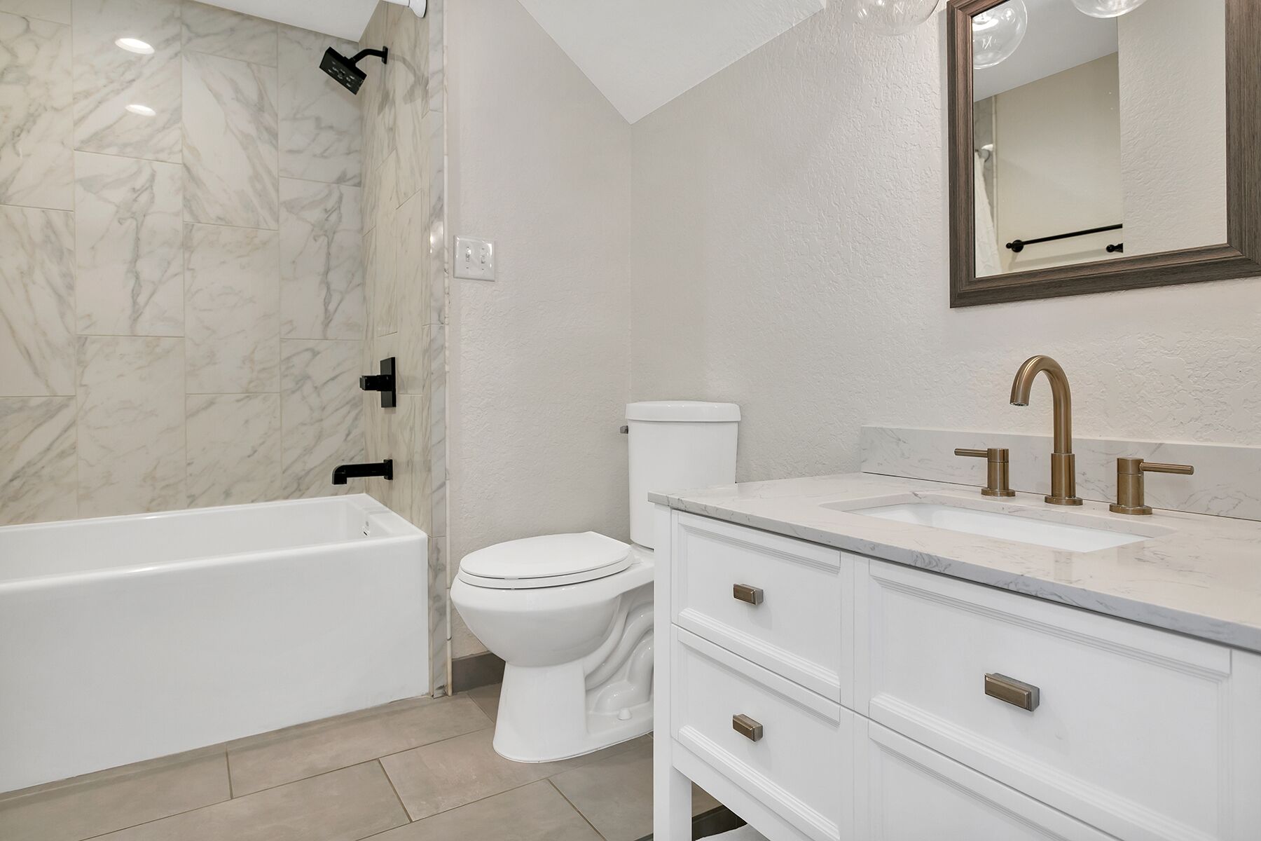 A bathroom with a bathtub, toilet, and vanity with a sink and mirror.