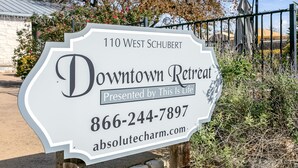 Letrero de Downtown Retreat en 110 West Schubert, presentado por This Is Life, con el número de contacto 866-244-7897 y sitio web absolutecharm.com.