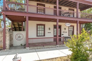 Een gebouw met twee verdiepingen, een balkon, een bord met 'ITZ INN' en een bord met 'Pontotoc Winery'.