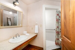 Een badkamer met een wastafel, spiegel en douchegordijn.