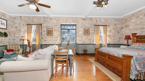 Une chambre à coucher avec un lit en bois, un canapé, une table à manger avec des chaises et un ventilateur de plafond.