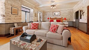 Un salon chaleureux avec un canapé beige, des coussins à motifs rouges et blancs, une table basse en bois et un ventilateur de plafond.