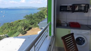 A balcony with a view of the sea, a washing machine, a microwave, and a sink. - sea view apartment on the Caribbean (Les Trois-Îlets)