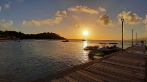 A wooden pier extending into calm waters with boats docked at the end.
