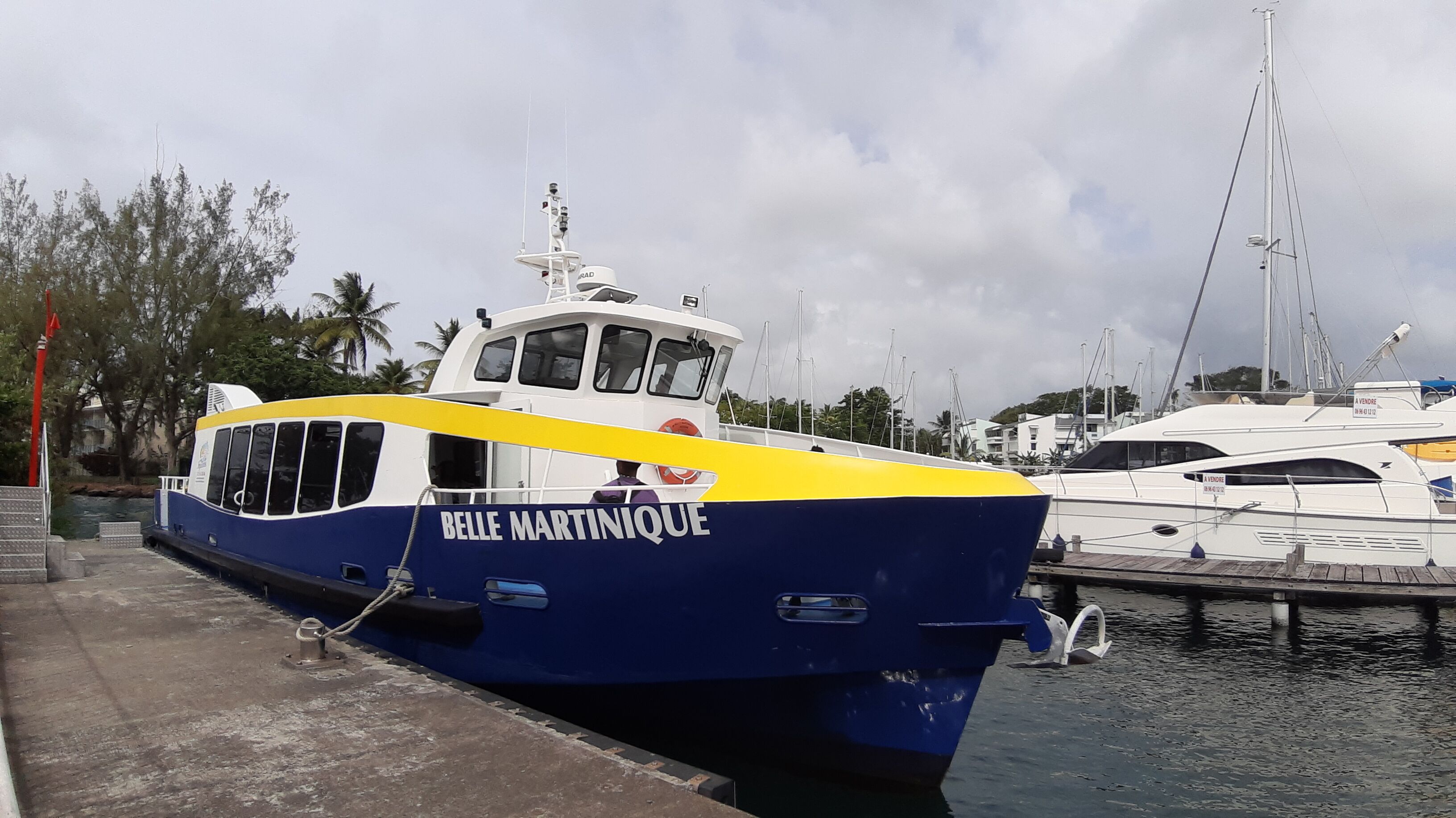 A boat named 'BELLE MARTINIQUE' docked at a marina with other boats in the background.