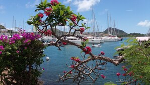 A marina with boats docked, surrounded by lush greenery and flowering plants. - sea view apartment on the Caribbean (Les Trois-Îlets)