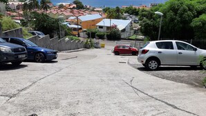 A parking area with several cars, including a blue sedan and a white hatchback. - sea view apartment on the Caribbean (Les Trois-Îlets)